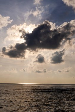 Sakin bir okyanusun üzerinde parlayan güneş ışınları