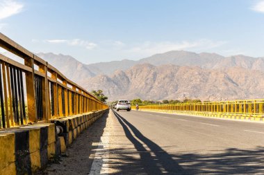 Uzak sıradağlara uzanan boş otoyol köprüsü yolculuğu ve özgürlüğü sembolize ediyor.