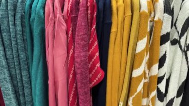 Satılık giyim mağazasının raflarında renkli kazaklar sergileniyor.