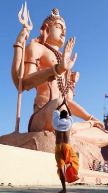 Adam, parlak gök kubbenin çerçevelediği dev tanrı figürüne saygı dolu bir jest yapıyor.