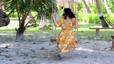 Açık havada salıncaktan hoşlanan bir kadınla tropik bir tatil.