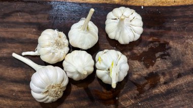 Taze sarımsak soğanları ahşap kesim tahtasının üst manzarasına yerleştirilmiş.
