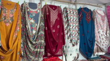 Yerel dükkanda giysi rafında asılı geleneksel Hint kurtileri