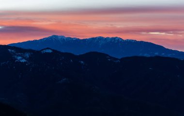 Gün batımında katmanlı dağ sıraları Renkli gökyüzü ve yumuşak alacakaranlık parlaklığıyla