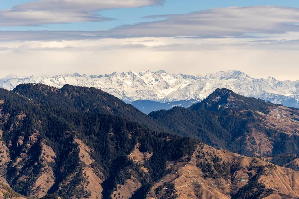 Himalaya dağ katmanları, arka planda kar örtüsü ve gün içinde dramatik gökyüzü.