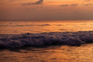 Pembe ve mor günbatımı gökyüzünün altında sakin bir okyanus yüzeyi