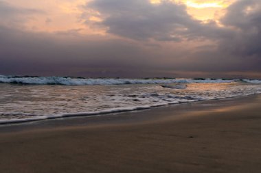 Fırtınalı okyanus ufkunu ve parlayan günbatımı gökyüzünü barındıran doğa manzarası