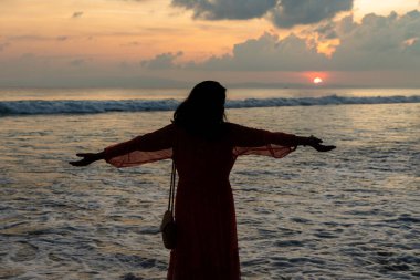 Sahilde sakin bir an. Kadın silueti parlayan ufka bakıyor.