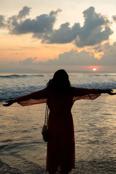 Okyanus esintisini kucaklayan kadın silueti ile huzurlu sahil gün batımı