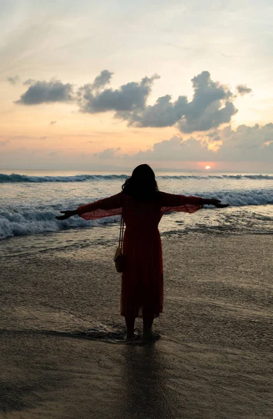 Kadın deniz kenarında günbatımının keyfini çıkarıyor.
