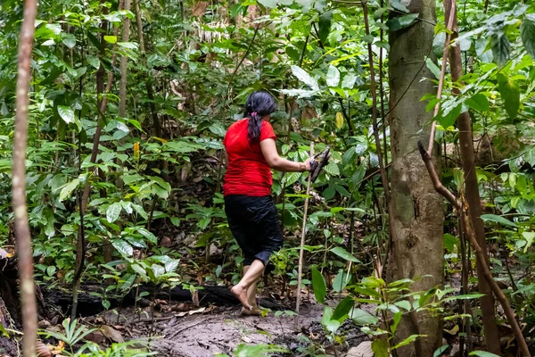 Yeşilliklerle çevrili sık orman yolunda yürüyen bir kadın.