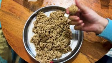 Kızarmış susam karışımıyla geleneksel Hint laddu pişirme işlemi