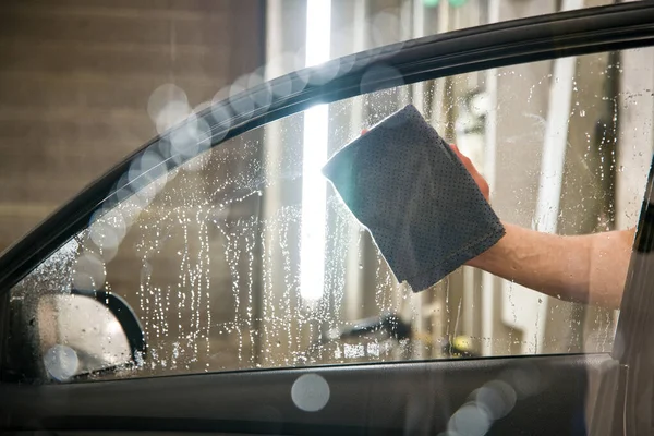 Mano con gamuza falsa limpia el vidrio de la puerta del coche — Foto de Stock