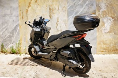 Güneşli bir günde arka kapağı kapalı modern siyah scooter. Kentsel ulaşım, seyahat ve özgürlük kavramı.