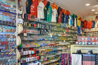 Sliema, Malta - 10.19.2025: Malta 'da renkli tişörtler, kupalar, mıknatıslar ve turistler için raflarda düzenli olarak düzenlenmiş hediyelerle canlı bir hediyelik eşya dükkanı.