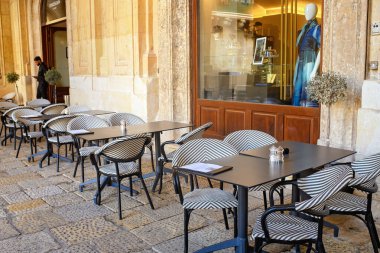 Valletta, Malta - 11.05.2025: Avrupa 'da bir caddenin penceresinin yanında boş masaları ve siyah-beyaz şablon sandalyeleri olan rahat bir açık kafe terası.
