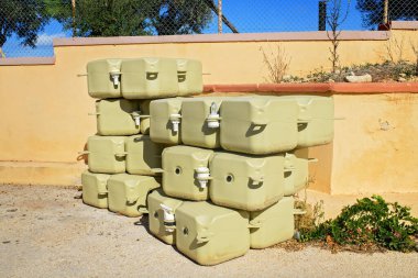 Açık havada güneşli bir duvarın altında yüzen deniz platformları inşa etmek için bej renkli duba blokları yığılmış..