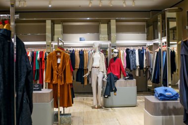 Sliema, Malta - 11.30.2025: Kara Cuma satışlarının başlaması için hazırlanan lüks bir çok markalı mağazada şık mankenler ve renkli elbise rafları.