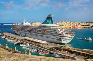 Valletta, Malta - 2 Aralık 2025: Artania yolcu gemisi turkuaz denize, yatlara, tahkimatlara ve Grand Harbour 'un tarihi mimarisine karşı manzaralı bir limana demirlemiştir..