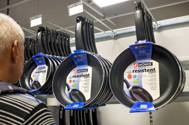 Sliema, Malta - 24 Aralık 2025: Bir adam bir mağazadaki raflara Monix Resistent Plus 'ın yapışmaz kızartma tavalarını asarak mutfak gereçleri sergisini inceliyor.