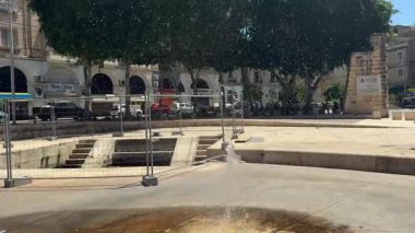 Bormla, Malta - 18 Ocak 2026: Şiddetli rüzgar şehir manzarasına karşı bir sokak çeşmesinden su damlacıklarını dağıtıyor.