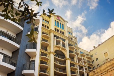 San Giljan, Malta - 25 Ekim 2025 Balkonlu Marriott Otel cephesinin alçak açılı görüntüsü ve yumuşak bulutlu parlak bir gökyüzüne karşı kemerli mimari.
