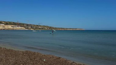 Mellieha, Malta - 6 Şubat 2026: Dalgıç kıyafetli genç bir kız, mavi denizde profesyonel bir eğitmenin rehberliği altında kanat folyosu üzerinde pratik yapıyor..