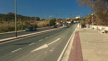 Mellieha, Malta - 6 Şubat 2026: Ilımlı araba trafiği, yol işaretleri ve toplu taşıma için donanımlı bir yer ile pürüzsüz bir asfalt yol manzarası.