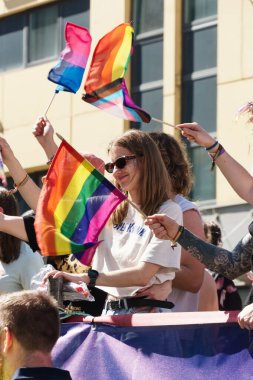 Oslo, Norveç - 28 Haziran 2025: Canlı bir geçit töreninde gökkuşağı bayrağı tutan genç kadın