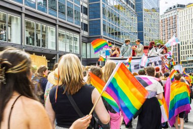 Oslo, Norveç - 28 Haziran 2025: İnsanlar gurur yürüyüşünde yürüyorlar, kentsel bir ortamda gökkuşağı bayrakları sallıyorlar