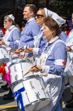 Oslo, Norveç - 28 Haziran 2025: Hemşire üniforması giyen ve gökkuşağı yüzlü davulcular Onur Yürüyüşü 'nde davul çalıyorlar