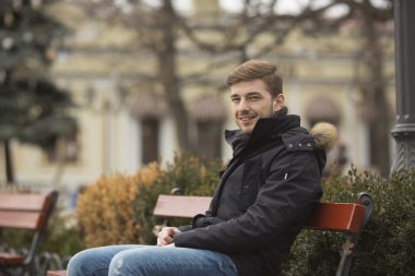 sonbahar parkta bankta oturan genç yakışıklı adam