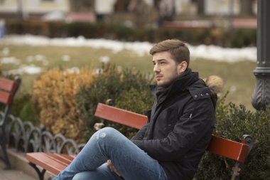 sonbahar parkta bankta oturan genç yakışıklı adam
