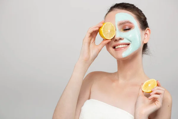 Beautiful young smile woman holding fresh lemon and orange slices. Skin care, spa, natural beauty and cosmetology concept, on gray background copyspace