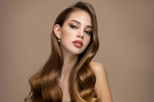 Uzun, güzel dalgalı saçlar. Kahverengi arka planda parlak saçlı bir kadının portresi. kopyala