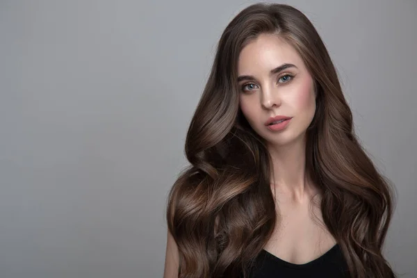 Uzun kahverengi bukleli bir kadının portresi. Gri bir arkaplanda