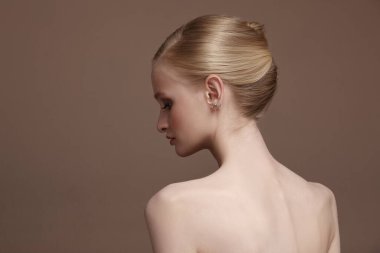 hairstyle gathered hair and pure natural skin of a woman on beige background