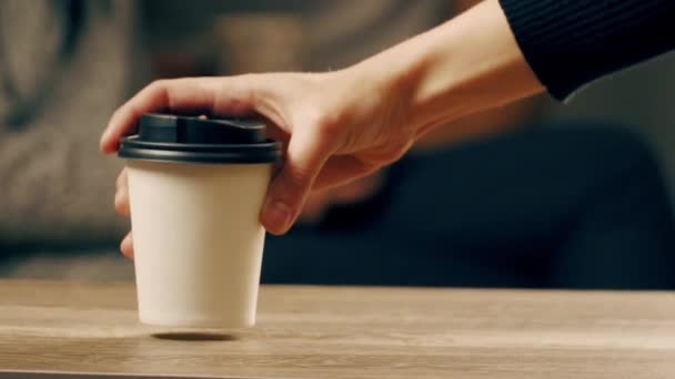 Een mans hand legde een koffiebeker op tafel. — Stockvideo