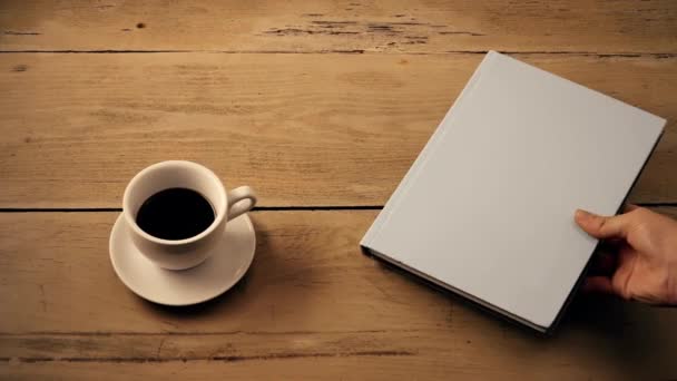 Panela tiro de uma xícara de café e livro em uma mesa de madeira — Vídeo de Stock