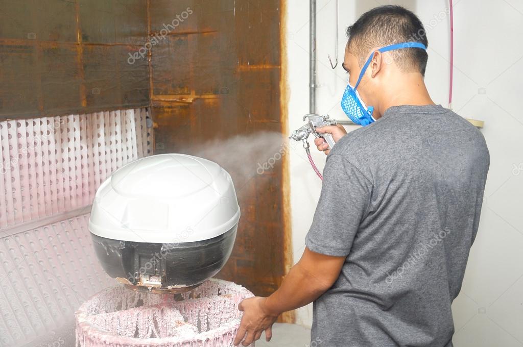 Worker painter wearing a protective mask painting a white color undercoat