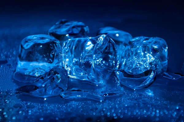 Derretimiento de cubos de hielo congelados iluminados con luz led de color azul en la oscuridad. —  Fotos de Stock