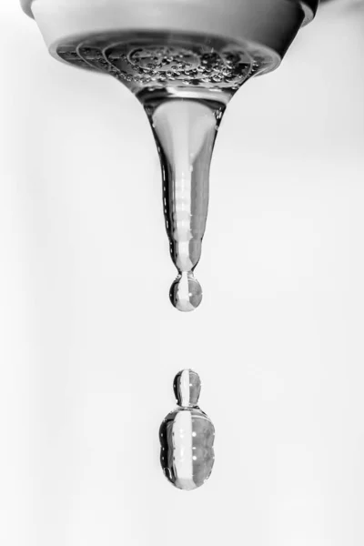 Kristallklart vatten droppar faller från kranen. Svart och vitt fotografi. — Stockfoto