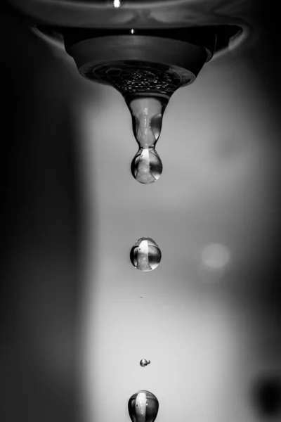 Klar vatten droppar faller från kranen. Kontrast svartvitt fotografi. — Stockfoto