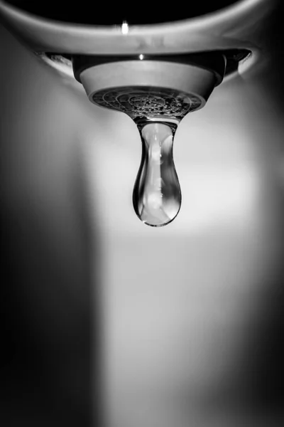 Klar vatten droppar faller från kranen. Kontrast svartvitt fotografi. — Stockfoto