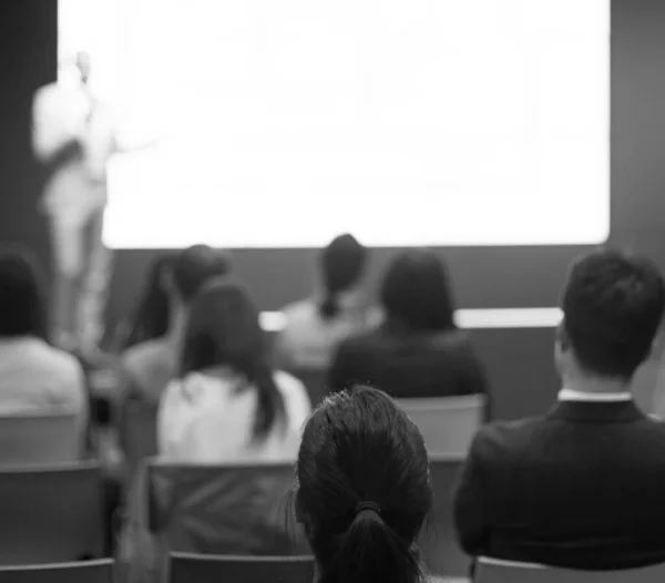 Speaker giving a talk at a corporate business conference.Audience in hall with presenter in front of presentation screen. Corporate executive giving speech during business and entrepreneur seminar.