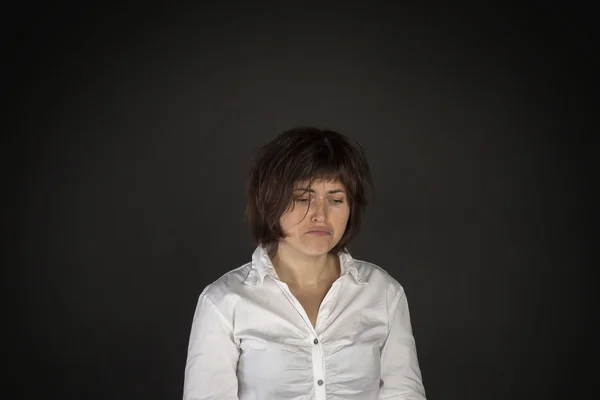 Portrait of young sad woman on black background