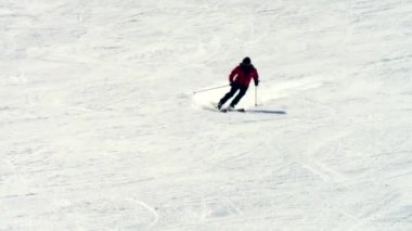 Kırmızı ceketli ve siyah pantolonlu bir kayakçı karlı bir dağ yamacından hızla iniyor. Güneşli bir günde 4K 'da çekildi. Hareketi, adrenalini ve kış sporlarını yakaladı..