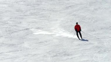 Turuncu kışlık ceketli ve koruyucu gözlüklü bir sporcu güvenli bir şekilde kayak yapıyor. 4K yavaş çekim, yumuşak hareket, hız ve kayak tekniğini vurguluyor.