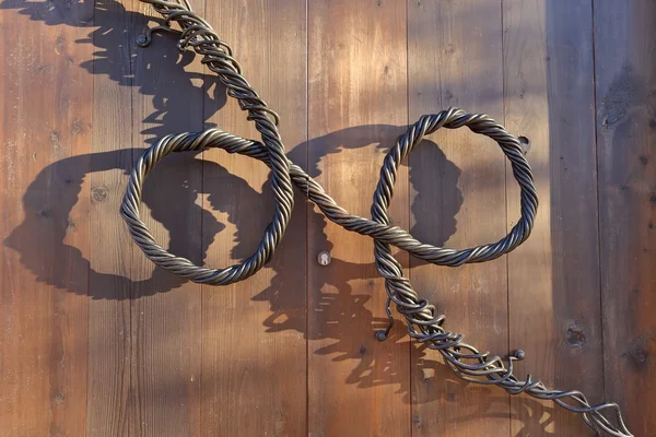 Dekoratif ahşap bir kapı üzerinde bükülmüş metal teller tanıtıcısı