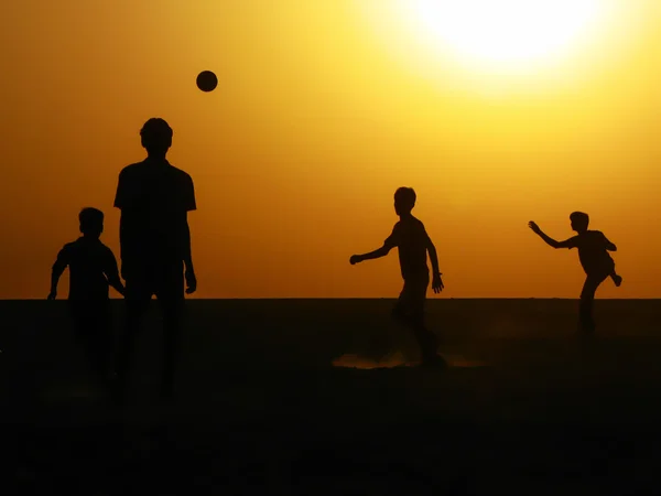 Güneş doğarken futbol oynayan çocuklar silüeti
